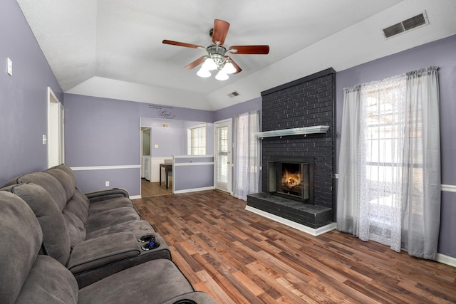 living area with visible vents, a brick fireplace, baseboards, and wood finished floors