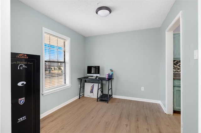 office area with baseboards, a textured ceiling, and light wood-style flooring