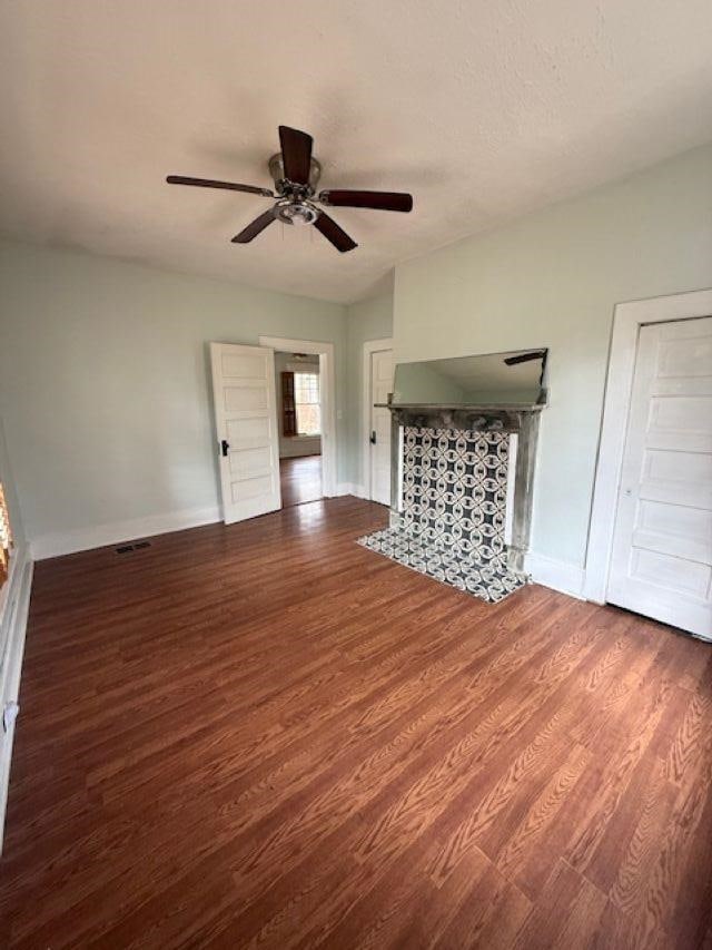 unfurnished living room with a ceiling fan, wood finished floors, baseboards, and a fireplace