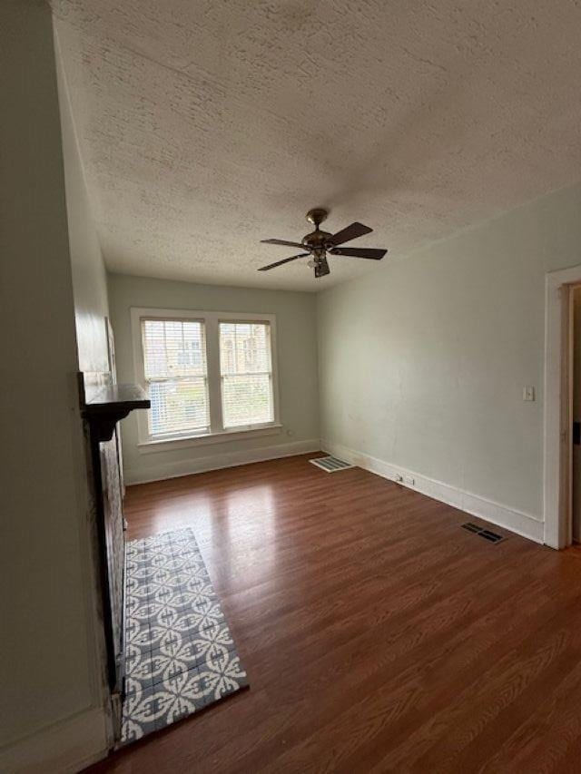 unfurnished living room featuring wood finished floors, baseboards, and a textured ceiling