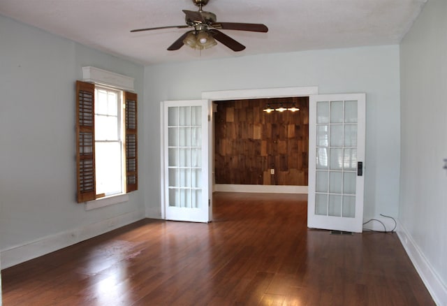 empty room featuring french doors, a ceiling fan, baseboards, and wood finished floors