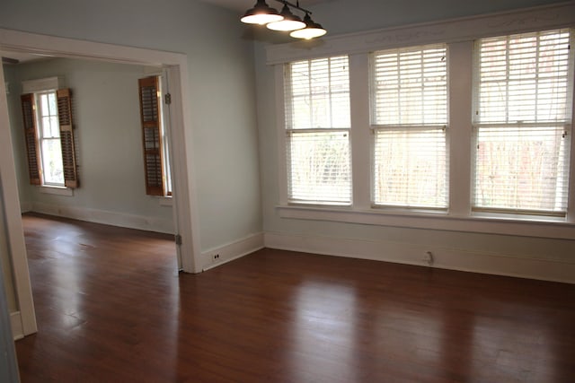 unfurnished room featuring a wealth of natural light, baseboards, and dark wood-style flooring