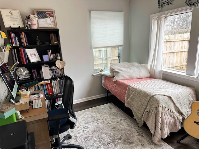 bedroom featuring baseboards, multiple windows, and wood finished floors