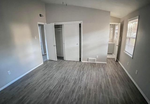 unfurnished bedroom featuring visible vents, baseboards, dark wood-style flooring, and vaulted ceiling