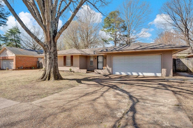 single story home featuring a garage, brick siding, driveway, and fence