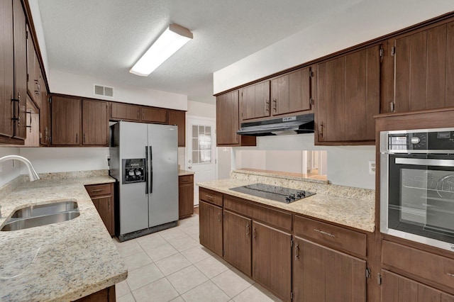 kitchen featuring visible vents, a sink, stainless steel appliances, under cabinet range hood, and a textured ceiling