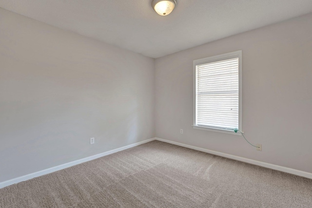 unfurnished room with carpet flooring and baseboards