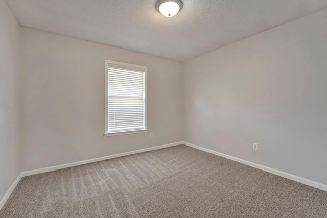 empty room featuring a textured ceiling, baseboards, and carpet