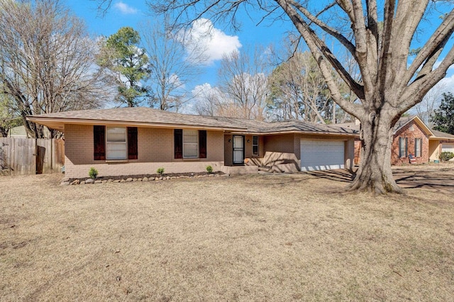 ranch-style home featuring a front yard, fence, driveway, an attached garage, and brick siding