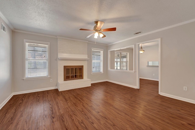 unfurnished living room with visible vents, a brick fireplace, dark wood finished floors, and crown molding