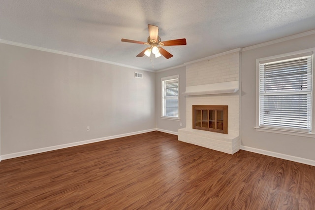 unfurnished living room with visible vents, ornamental molding, a textured ceiling, wood finished floors, and a brick fireplace