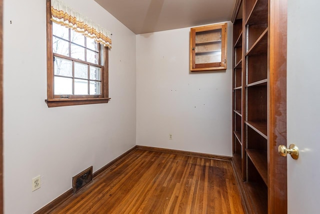 unfurnished room with dark wood finished floors, visible vents, and baseboards