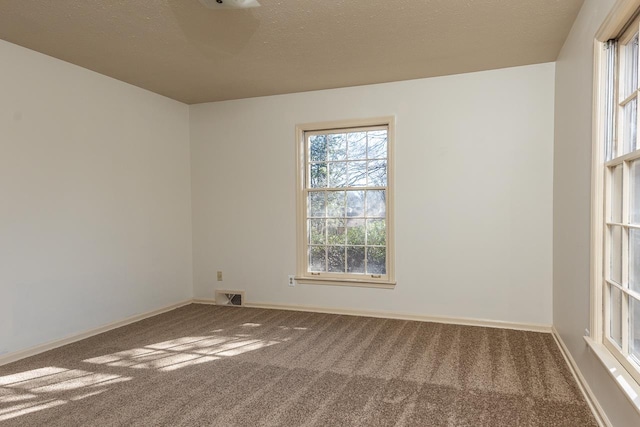 unfurnished room featuring carpet flooring, baseboards, visible vents, and a textured ceiling