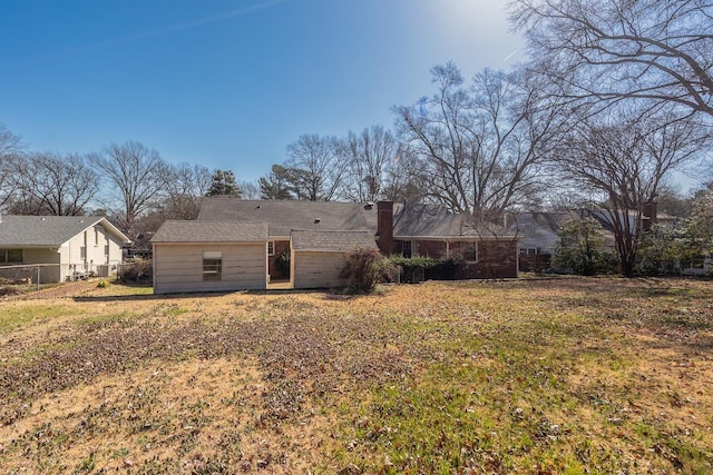 rear view of property with a yard, fence, and a chimney