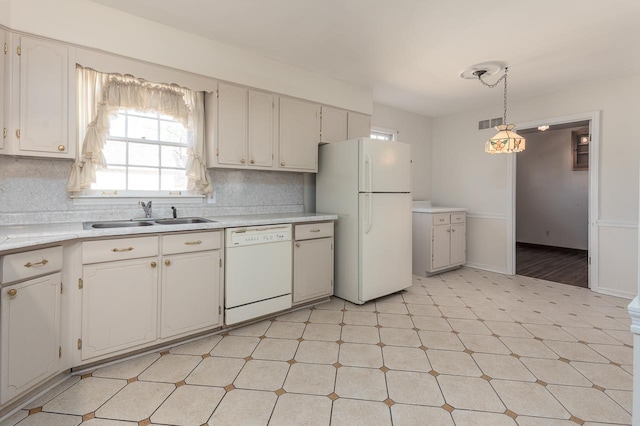 kitchen featuring tasteful backsplash, light floors, light countertops, white appliances, and a sink