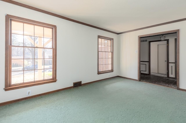 carpeted spare room featuring visible vents, baseboards, and ornamental molding