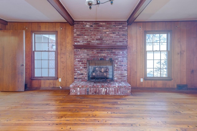 unfurnished living room with beamed ceiling, a brick fireplace, and hardwood / wood-style flooring