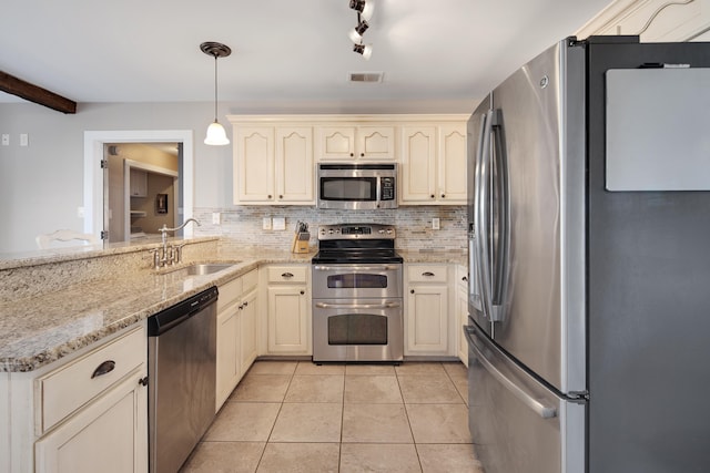 kitchen featuring visible vents, backsplash, cream cabinetry, stainless steel appliances, and a sink