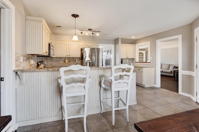 kitchen with visible vents, backsplash, appliances with stainless steel finishes, a peninsula, and light tile patterned flooring