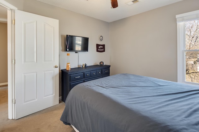 bedroom with a ceiling fan, visible vents, and light carpet