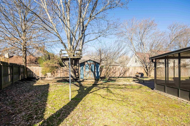 view of yard with a fenced backyard, a shed, an outdoor structure, and a sunroom