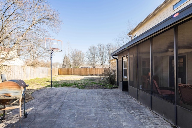 view of patio with area for grilling, a fenced backyard, and a sunroom