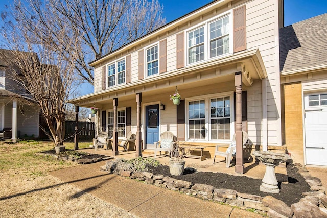 view of front of home featuring fence, covered porch, and a shingled roof