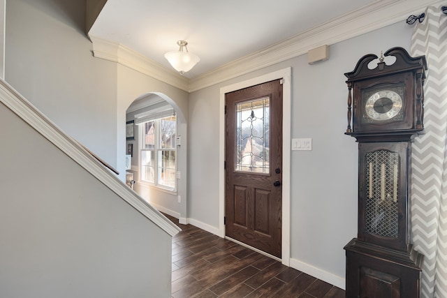 foyer entrance with wood finish floors, baseboards, arched walkways, and ornamental molding