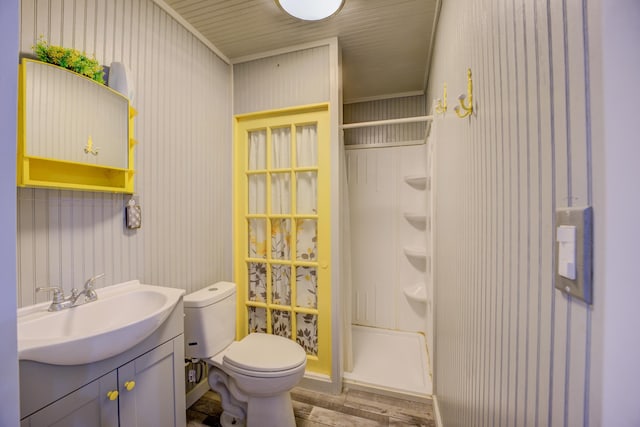 bathroom with a shower stall, toilet, vanity, and wood finished floors