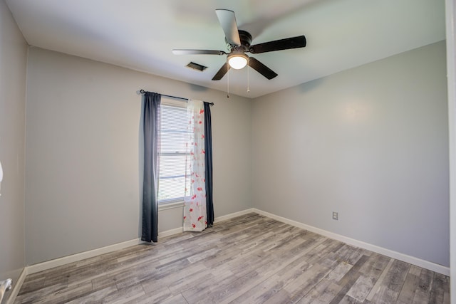 spare room featuring ceiling fan, visible vents, baseboards, and light wood-style flooring