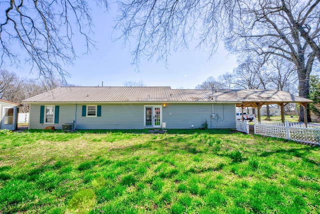 rear view of property featuring central AC, fence, french doors, metal roof, and a carport