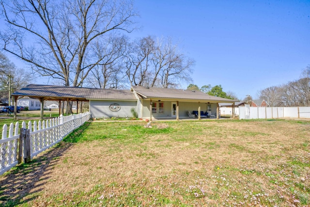 rear view of property featuring a carport, a yard, a fenced backyard, and a patio