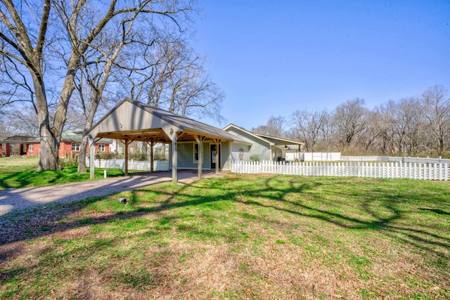 view of yard featuring a carport, driveway, and fence