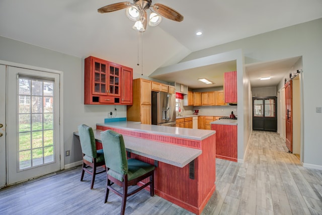 kitchen with a peninsula, light wood-style flooring, light countertops, and stainless steel fridge