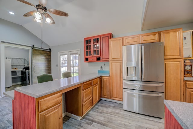 kitchen with lofted ceiling, a peninsula, freestanding refrigerator, ceiling fan, and stainless steel fridge