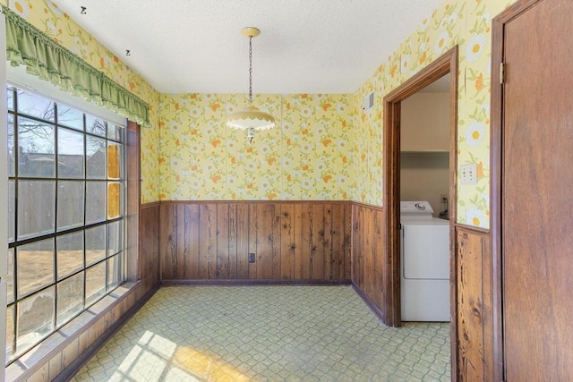 unfurnished room with washer / dryer, wainscoting, and wallpapered walls