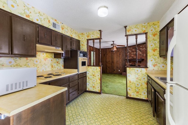 kitchen with wallpapered walls, white appliances, under cabinet range hood, and a textured ceiling