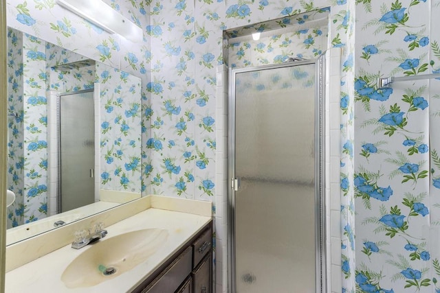 full bath with wallpapered walls, a shower stall, and vanity