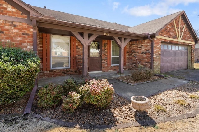 doorway to property with brick siding, a shingled roof, a porch, driveway, and an attached garage