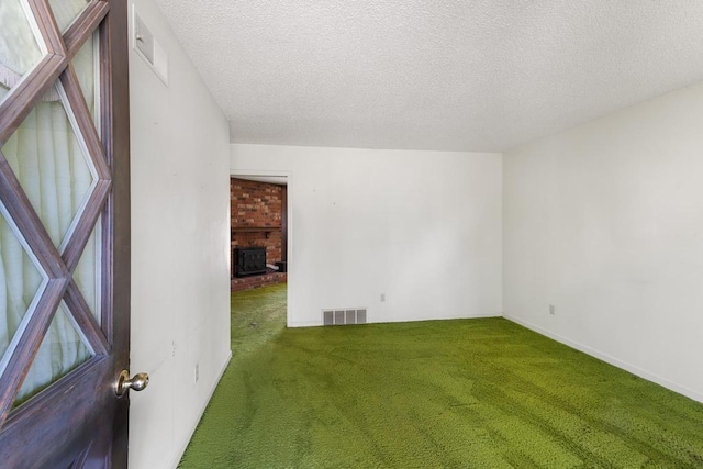 carpeted empty room featuring visible vents, a brick fireplace, and a textured ceiling