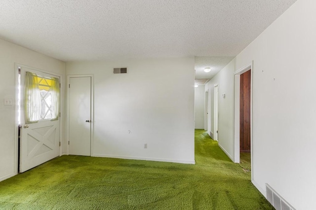 carpeted entrance foyer with visible vents, baseboards, and a textured ceiling