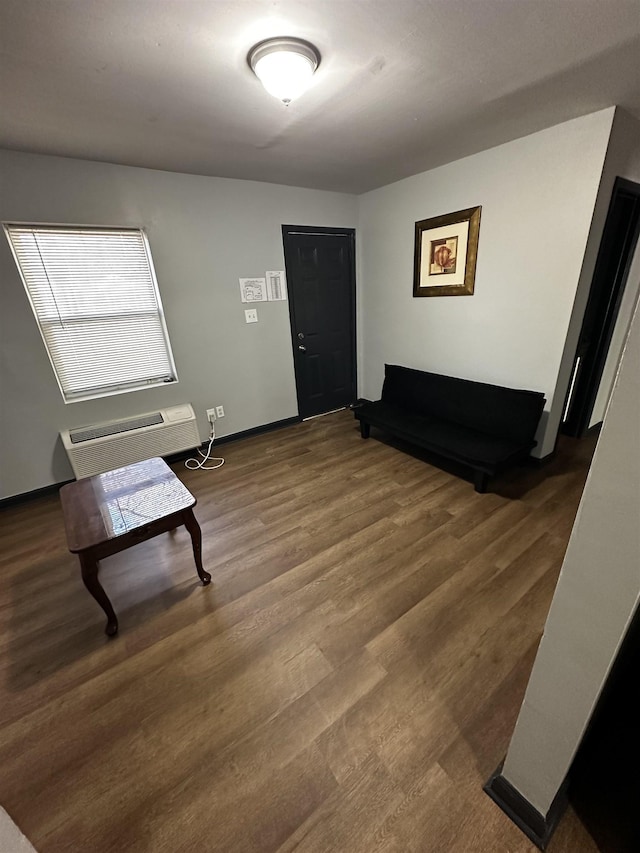 living area with an AC wall unit, baseboards, and wood finished floors