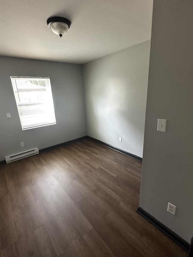 empty room featuring dark wood-style floors, baseboards, and a baseboard radiator