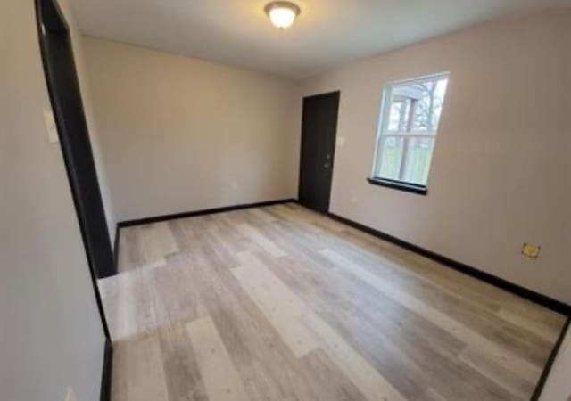 spare room with baseboards and wood finished floors