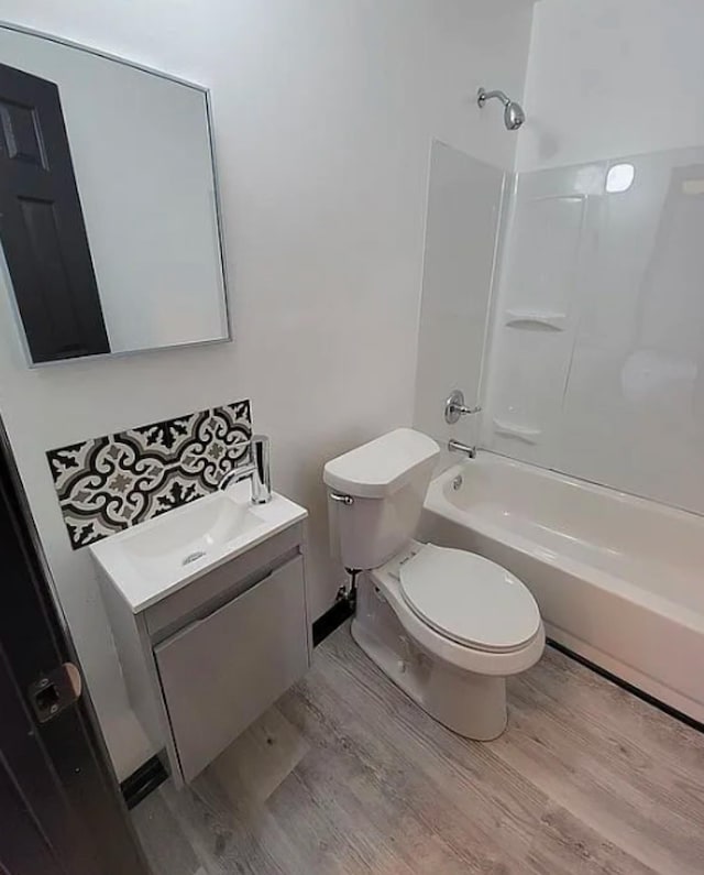 full bath with toilet,  shower combination, wood finished floors, and vanity