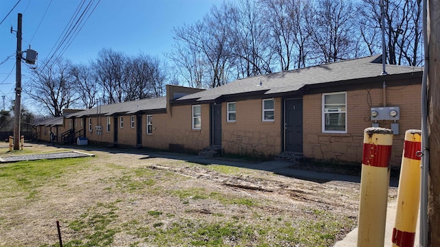 view of property exterior with entry steps, a lawn, a residential view, and roof with shingles