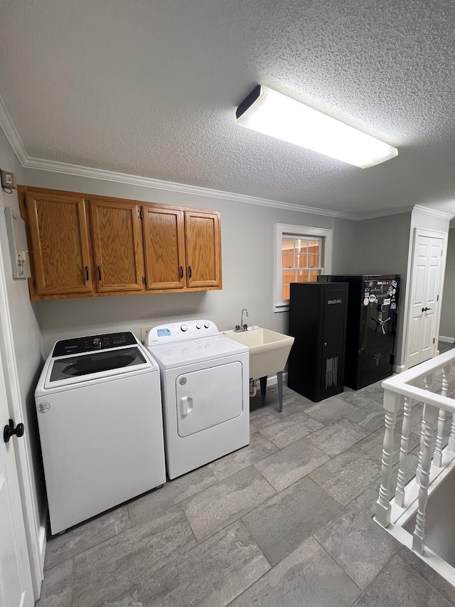 laundry area featuring a sink, cabinet space, crown molding, and separate washer and dryer