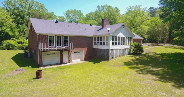 back of property with a sunroom, brick siding, driveway, and a lawn