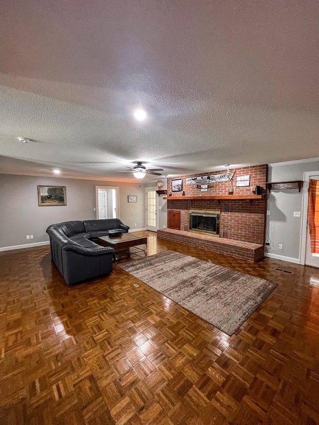 living room with a textured ceiling, a brick fireplace, baseboards, and ceiling fan