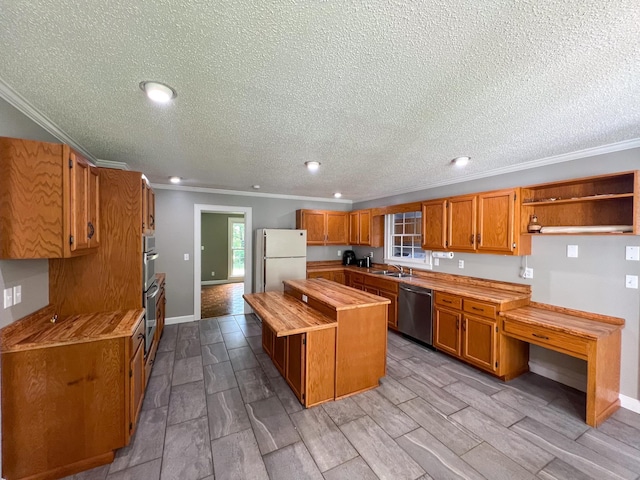 kitchen with a kitchen island, dishwasher, brown cabinets, freestanding refrigerator, and a sink